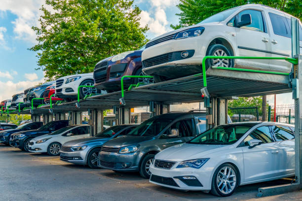 Two-level outdoor car parking system with cars parked on both lower and elevated platforms, surrounded by trees and a fence under a partly cloudy sky—ideal for Car Transport Bay Shore, NY services or convenient Car Shipping Bay Shore, NY needs.